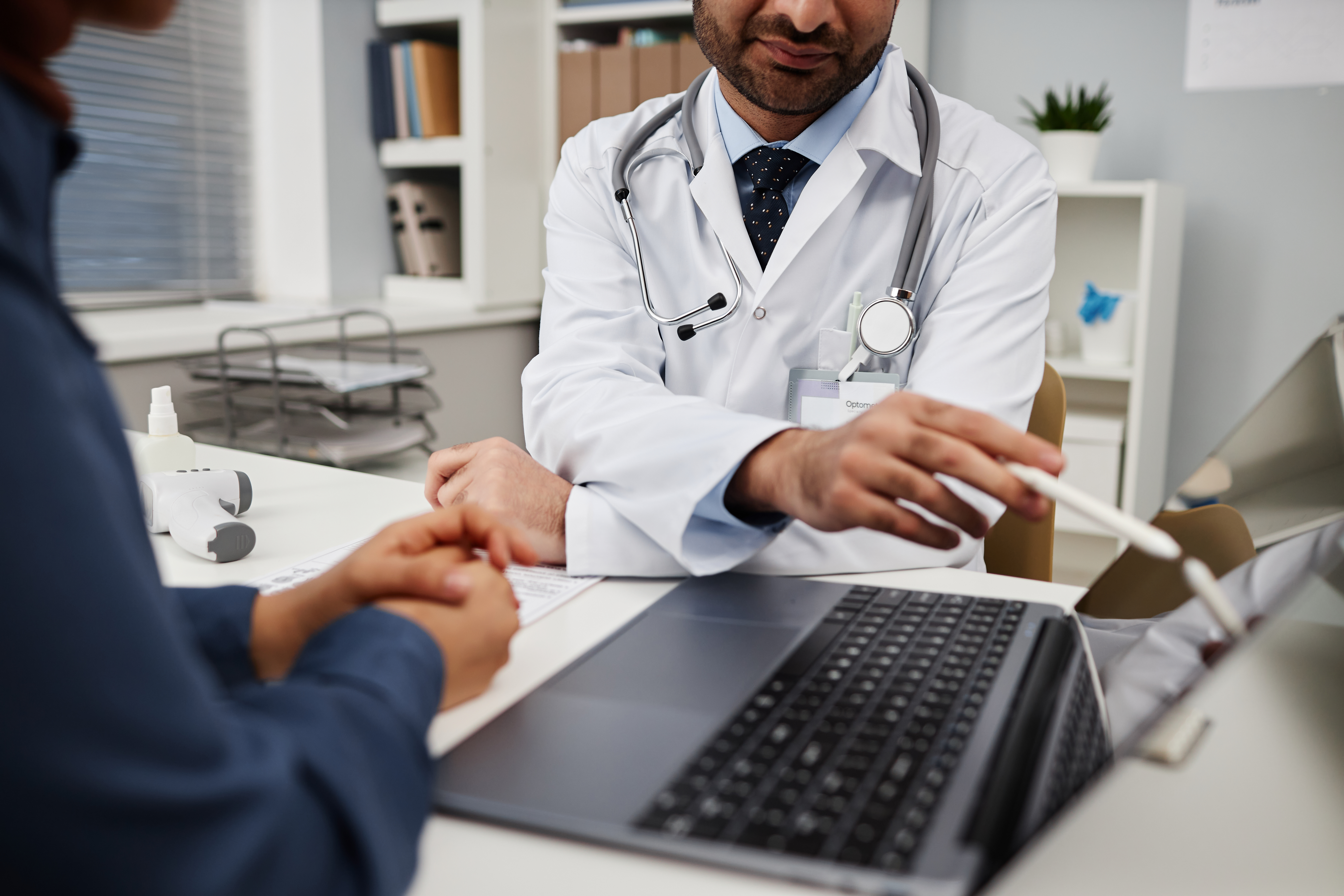 Healthcare practitioner showing information on laptop to patient